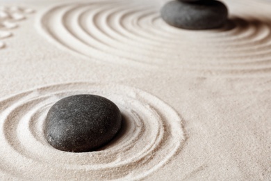 Photo of Zen garden stones on sand with pattern. Meditation and harmony