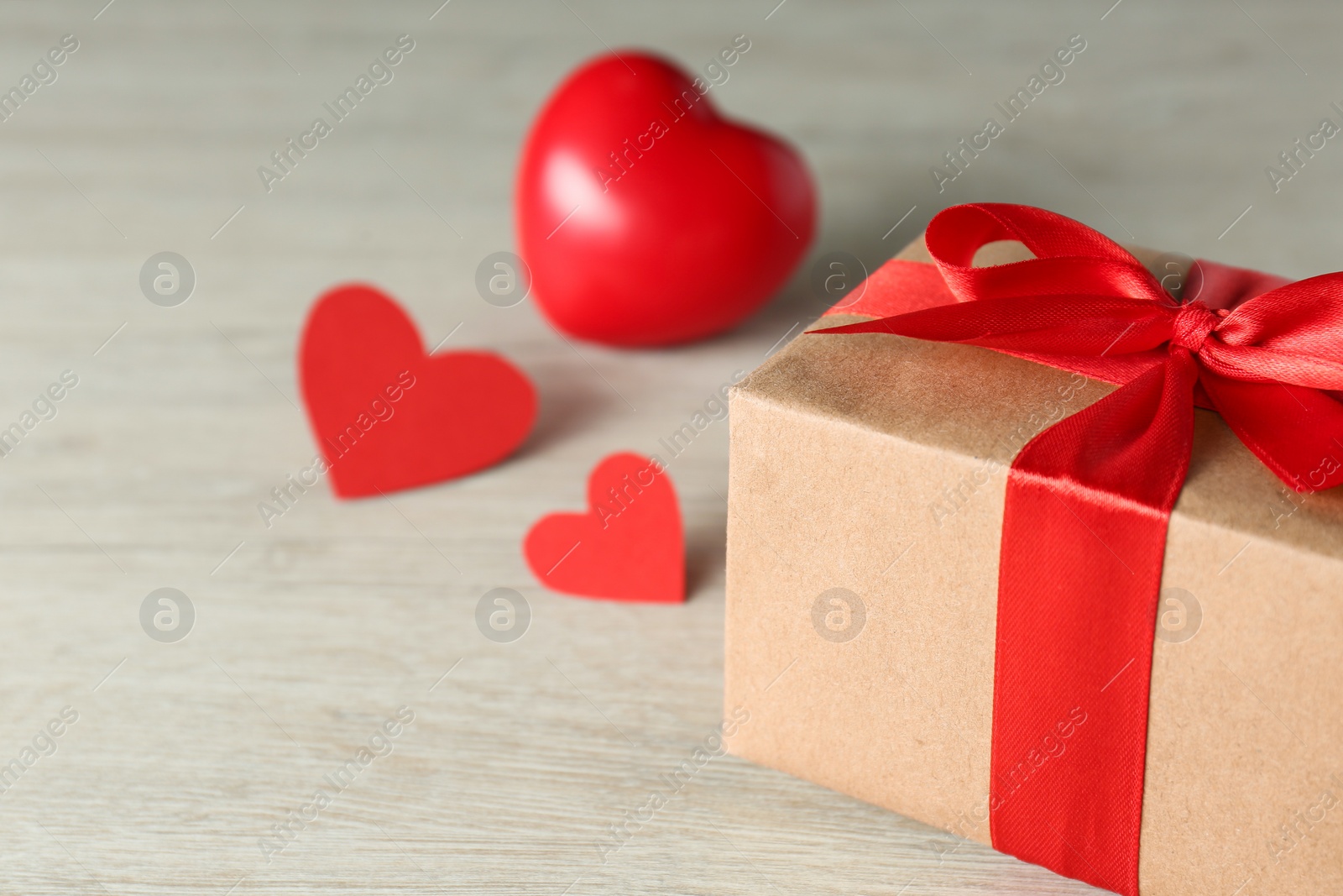 Photo of Beautiful gift box with decorative red hearts on white wooden table, closeup