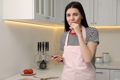 Young woman cutting finger with knife while cooking in kitchen. Space for text