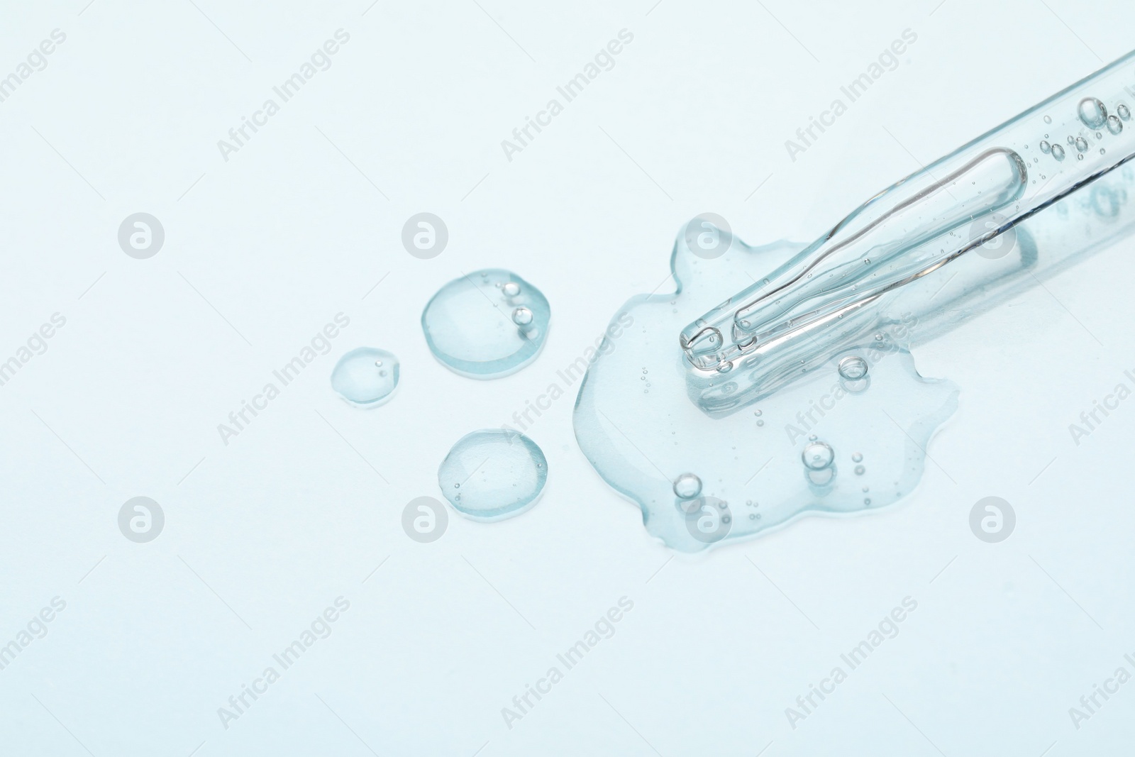 Photo of Glass pipette and transparent liquid on light background, top view. Space for text