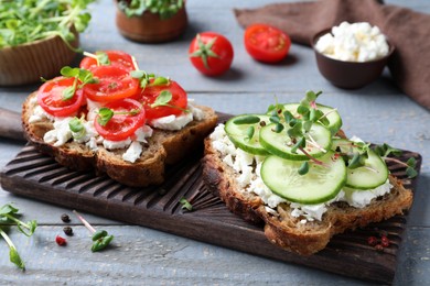 Photo of Delicious sandwiches with vegetables, cheese and microgreens on grey wooden table