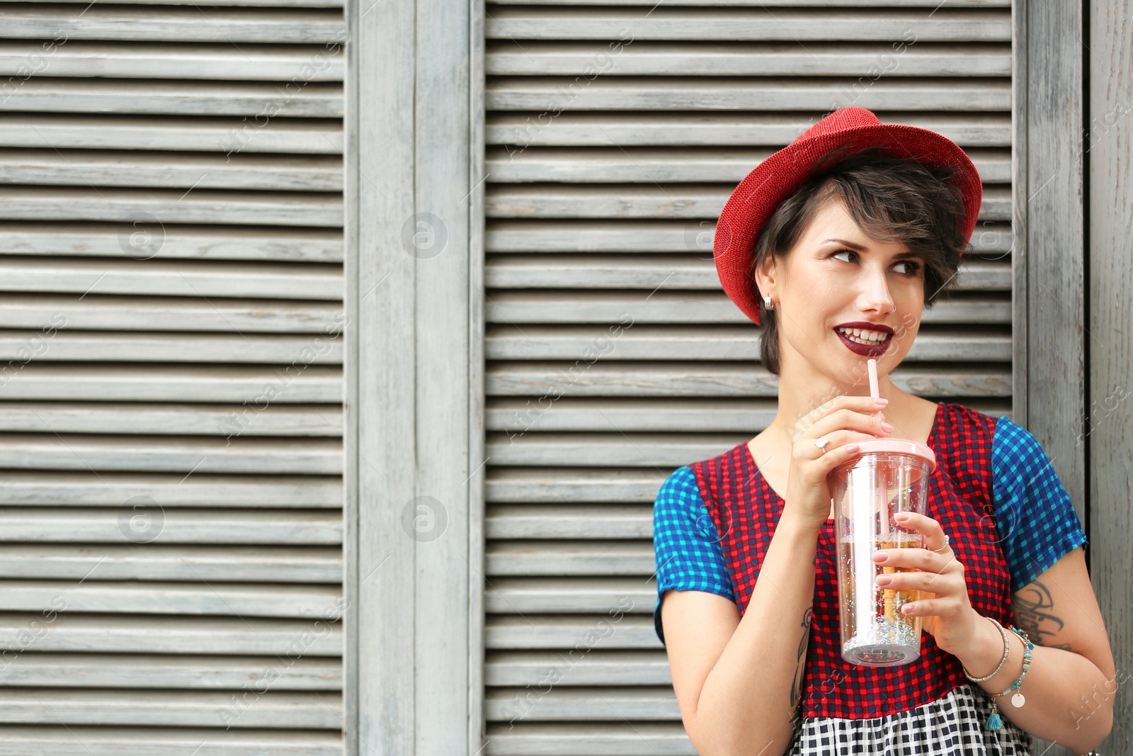 Photo of Young woman with cup of tasty lemonade near wooden wall