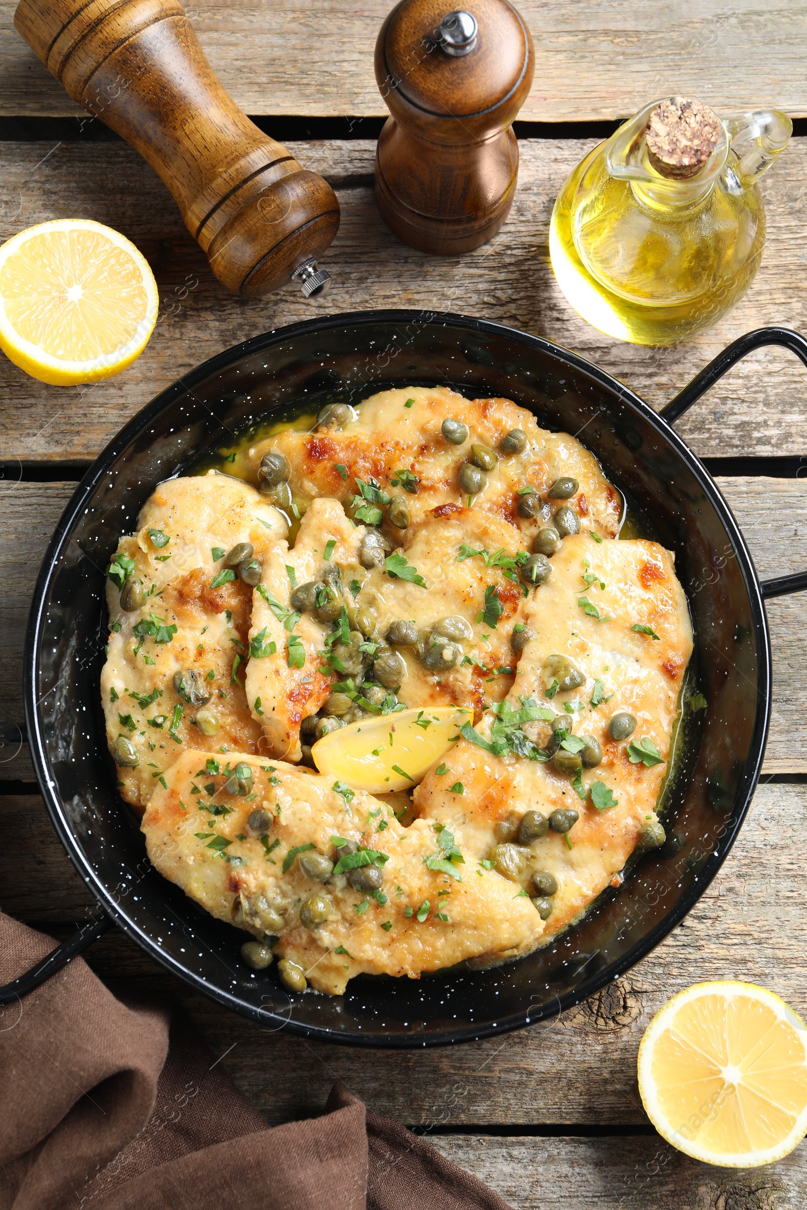 Photo of Delicious chicken piccata with herbs and lemon on wooden table, flat lay