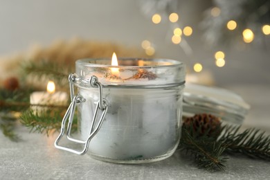 Photo of Burning scented conifer candle and Christmas decor on grey table