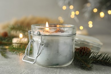 Burning scented conifer candle and Christmas decor on grey table