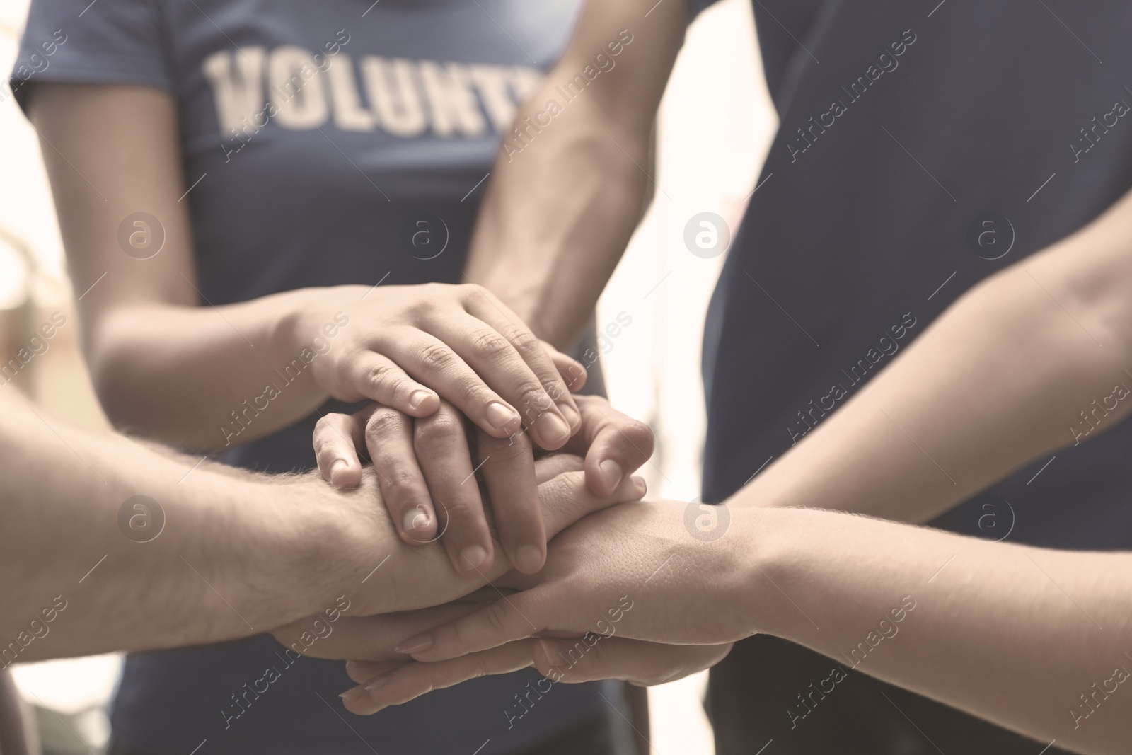 Image of Group of volunteers joining hands together, closeup. Black and white effect