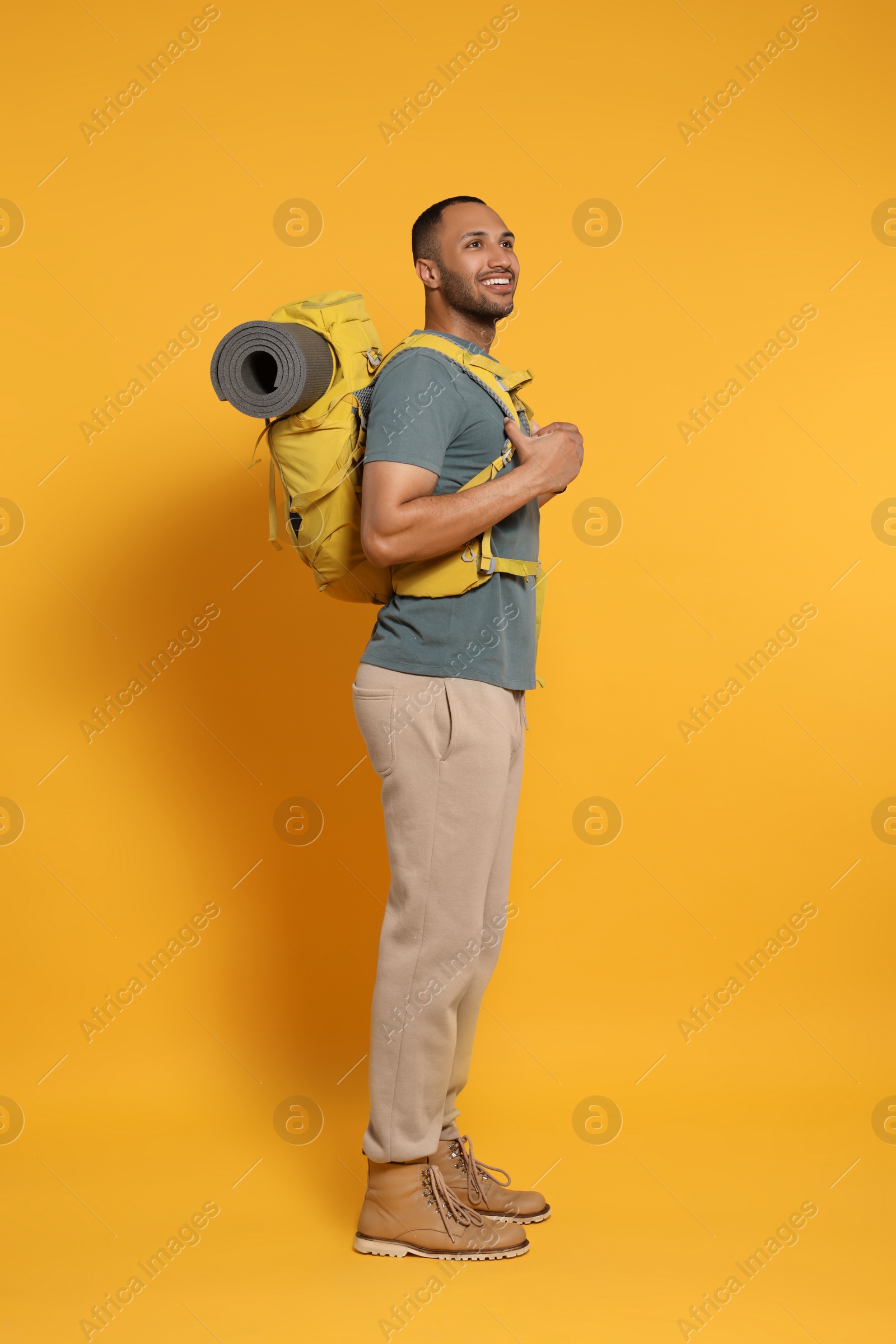 Photo of Happy tourist with backpack on yellow background