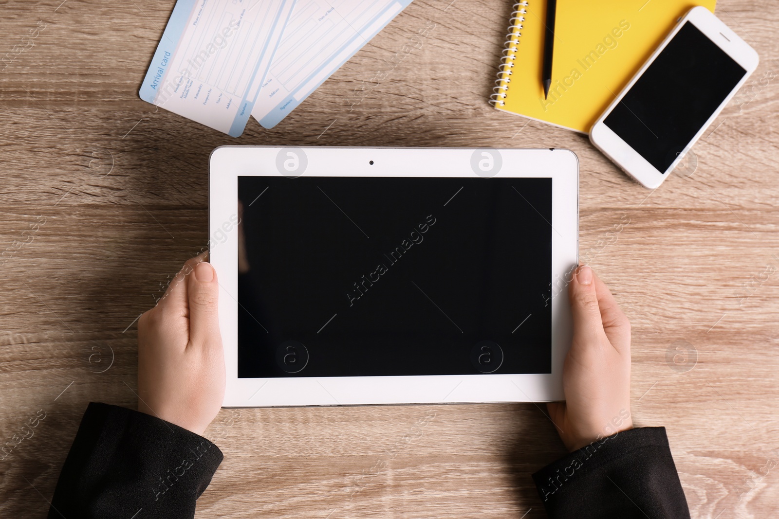 Photo of Woman holding tablet with blank screen on wooden background, top view. Travel agency