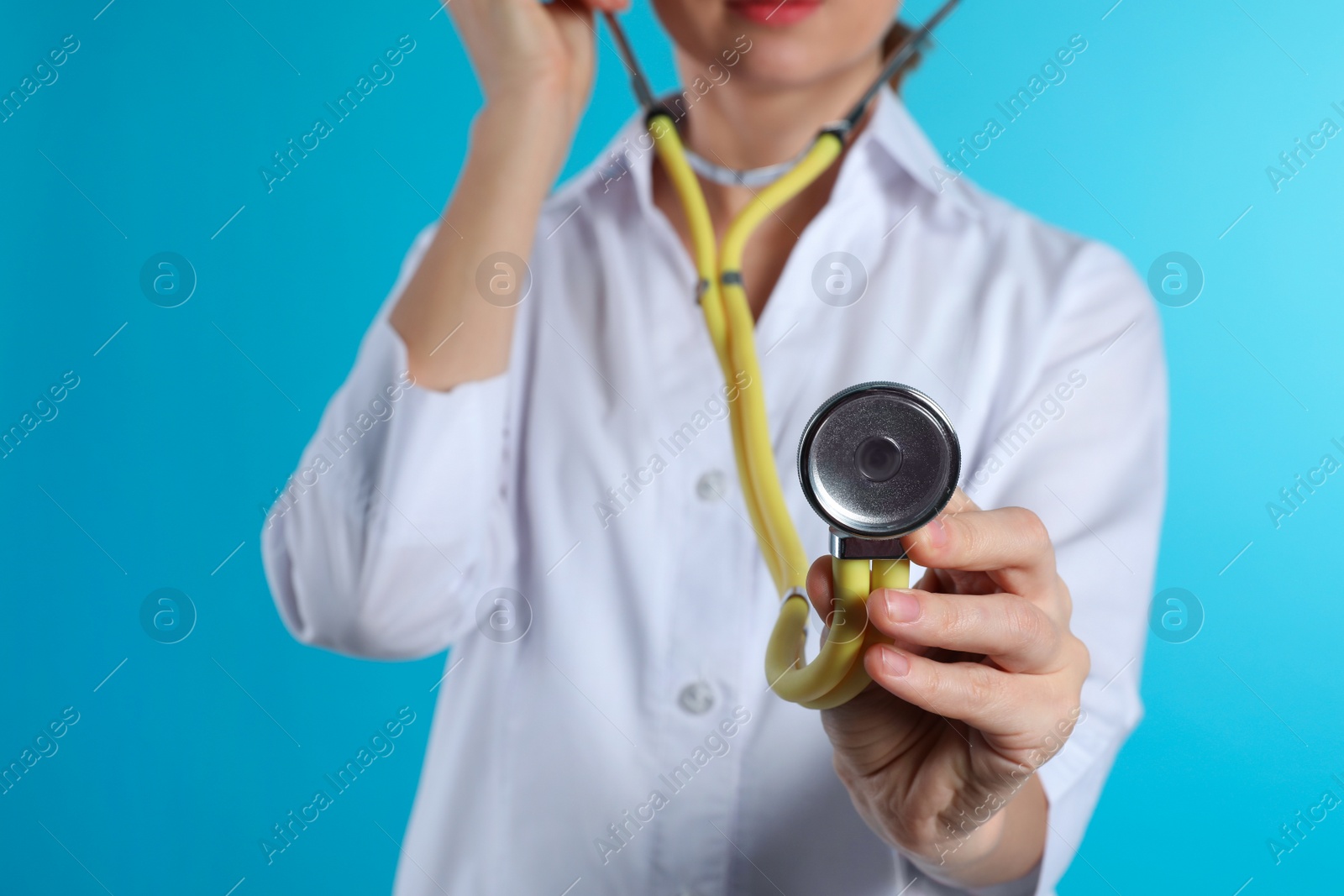 Photo of Female doctor holding stethoscope on color background, closeup. Medical object