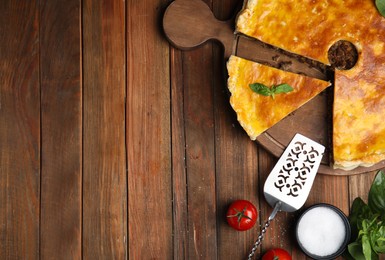 Photo of Delicious pie with minced meat and ingredients on wooden table, flat lay. Space for text