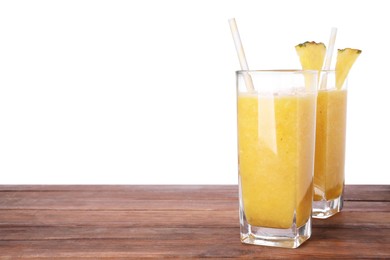 Tasty pineapple smoothie on wooden table against white background, space for text