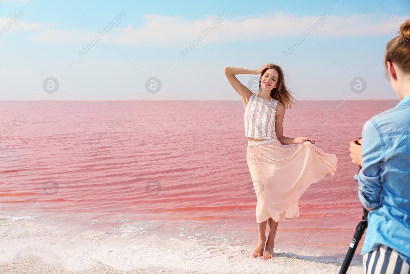 Photo of Female photographer taking pictures of model near pink lake