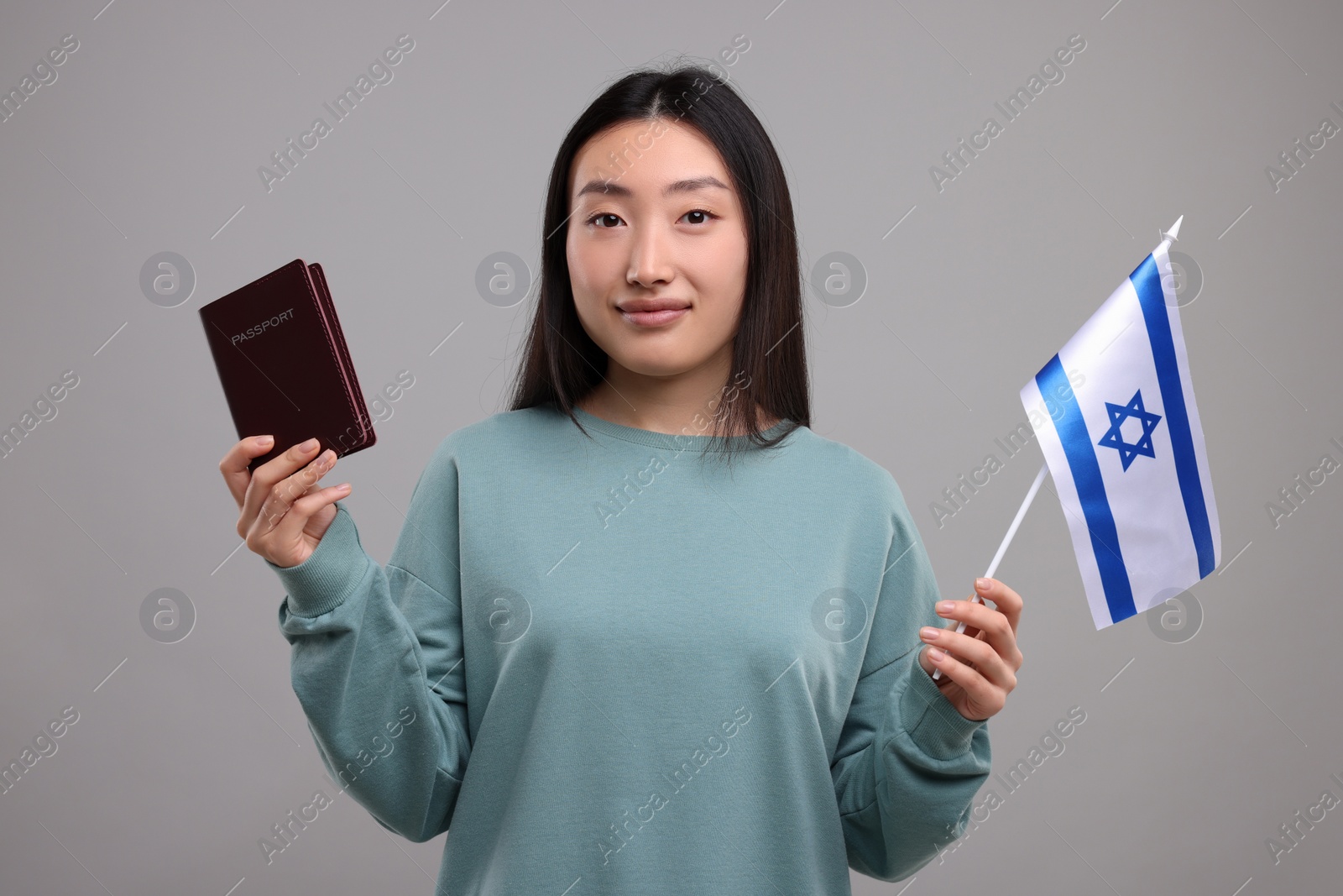 Photo of Immigration to Israel. Woman with passport and flag on grey background