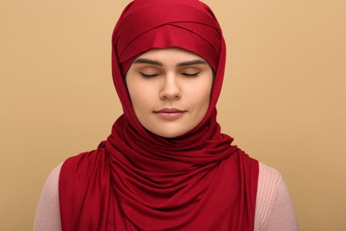 Portrait of Muslim woman in hijab on beige background