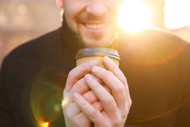 Man with cup of coffee on city street in morning, closeup