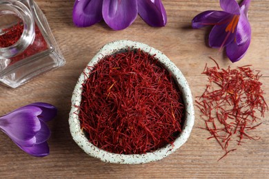 Photo of Dried saffron and crocus flowers on wooden table, flat lay