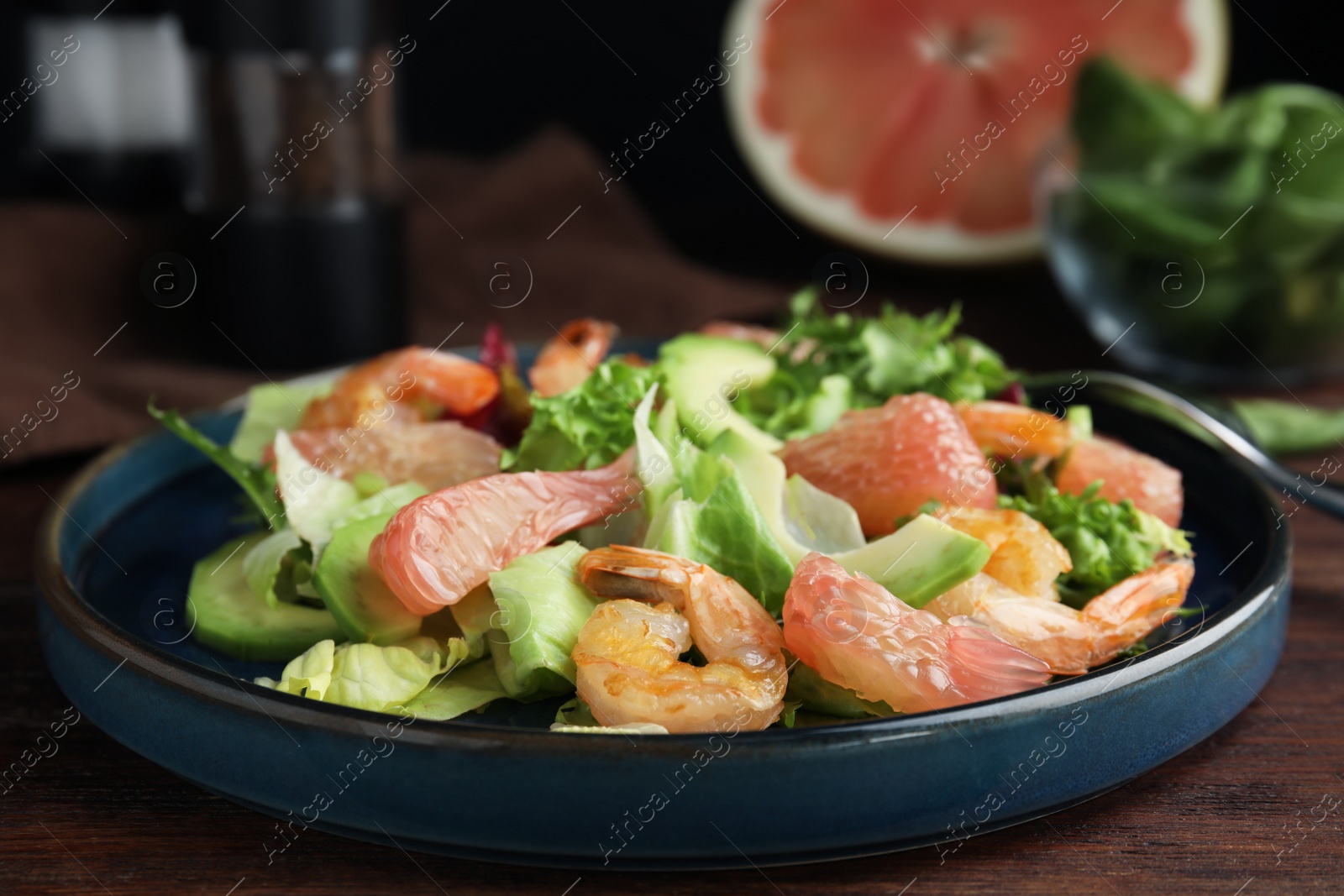 Photo of Delicious pomelo salad with shrimps served on wooden table, closeup