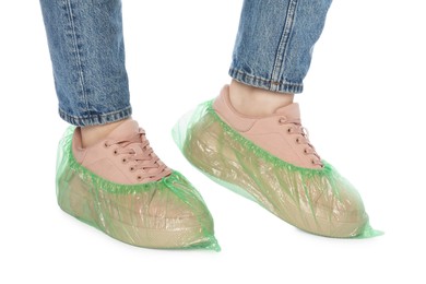 Photo of Woman wearing green shoe covers onto her sneakers against white background, closeup