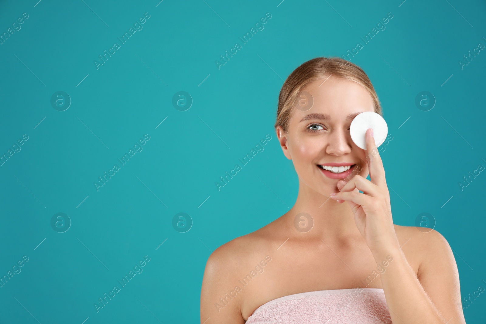 Photo of Beautiful young woman with cotton pad on turquoise background. Space for text