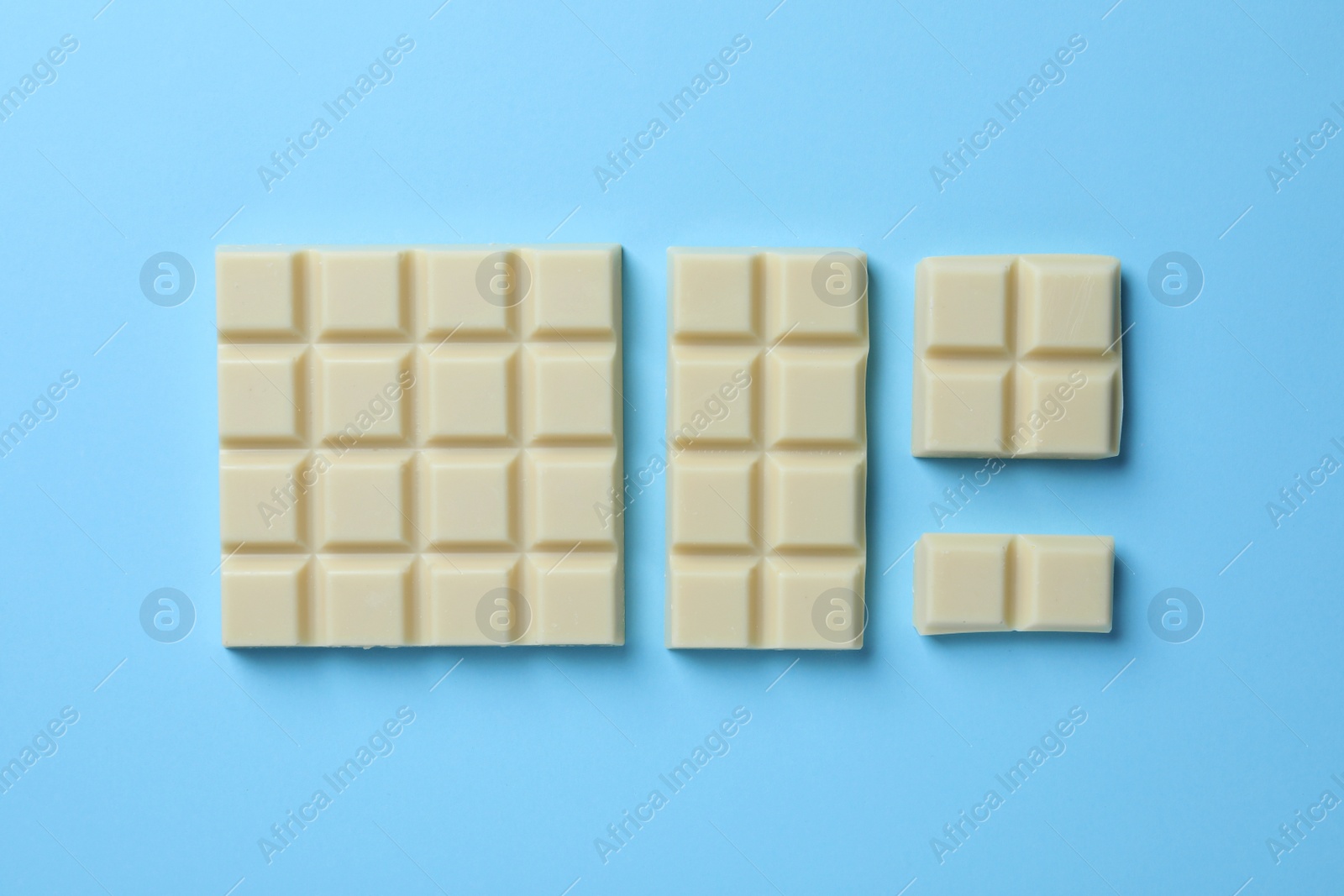 Photo of Tasty white chocolate on light blue background, flat lay