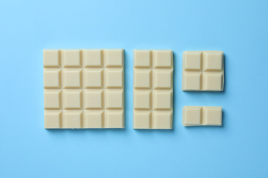 Photo of Tasty white chocolate on light blue background, flat lay