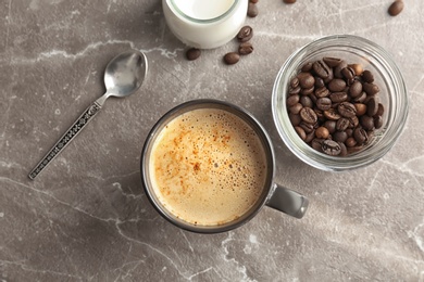 Cup of aromatic hot coffee, jars with milk and beans on table, top view