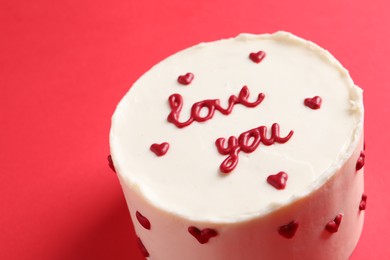 Photo of Bento cake with text Love You on red table, closeup. St. Valentine's day surprise