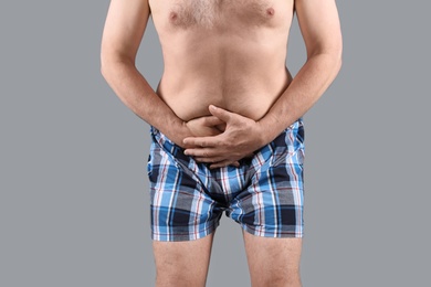 Photo of Mature man with urological problems suffering from pain on grey background