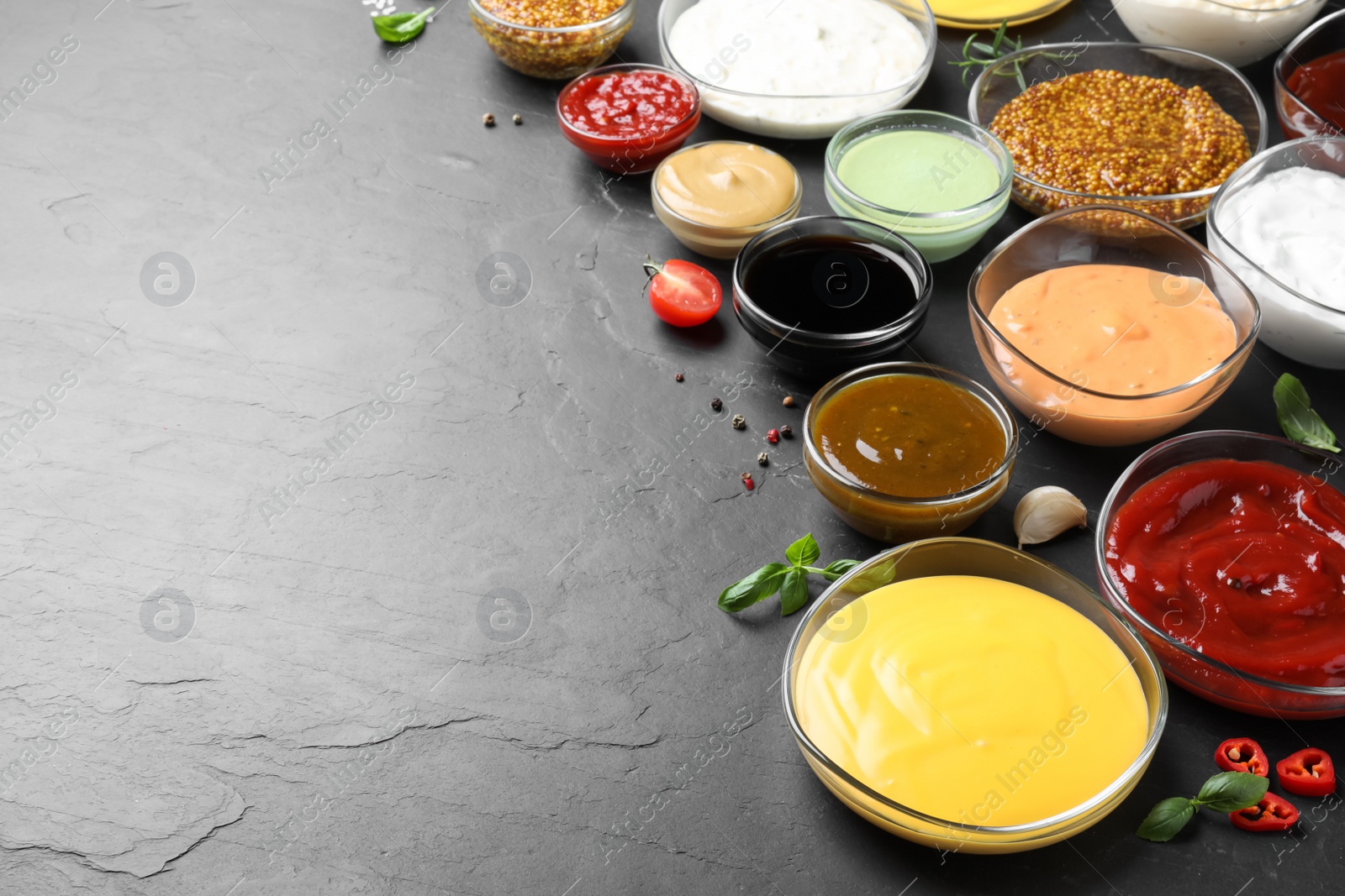 Photo of Many different sauces on black table, space for text