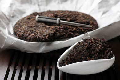 Photo of Aromatic pu-erh on wooden tray, closeup. Fermented tea