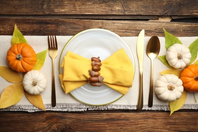 Seasonal table setting with pumpkins and other autumn decor on wooden background, flat lay