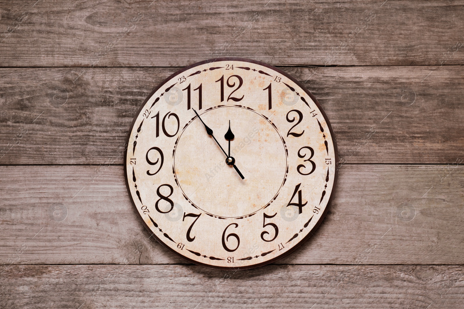 Photo of Clock showing five minutes until midnight on wooden table, top view. New Year countdown