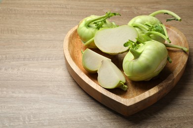 Whole and cut kohlrabi plants on wooden table