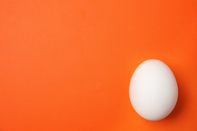 Photo of Raw chicken egg on color background, top view. Space for text