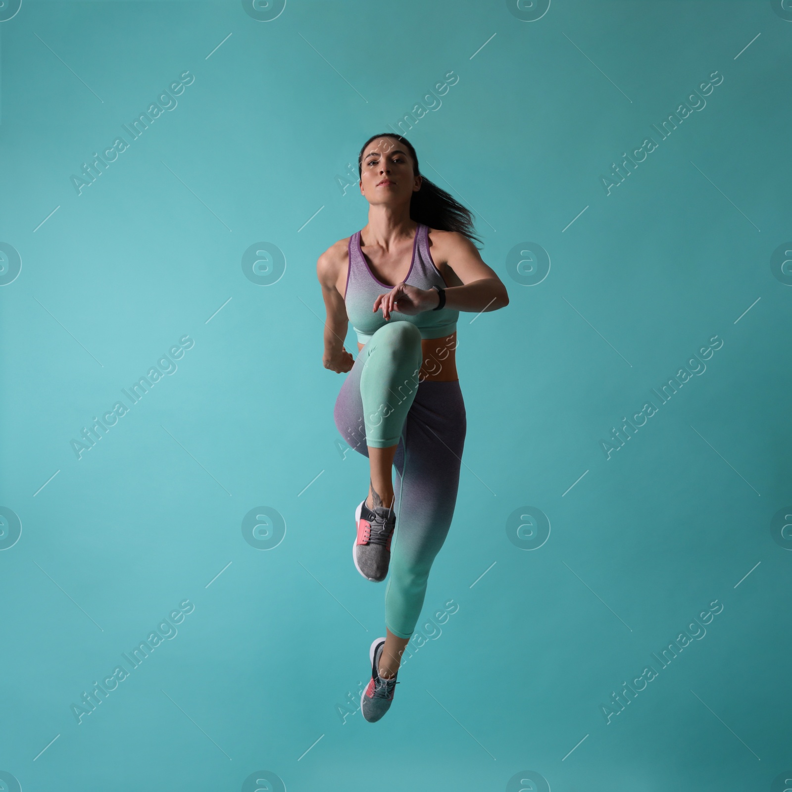 Photo of Athletic young woman running on turquoise background