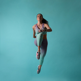 Photo of Athletic young woman running on turquoise background