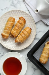 Delicious sausage rolls and hot drink on white marble table, flat lay