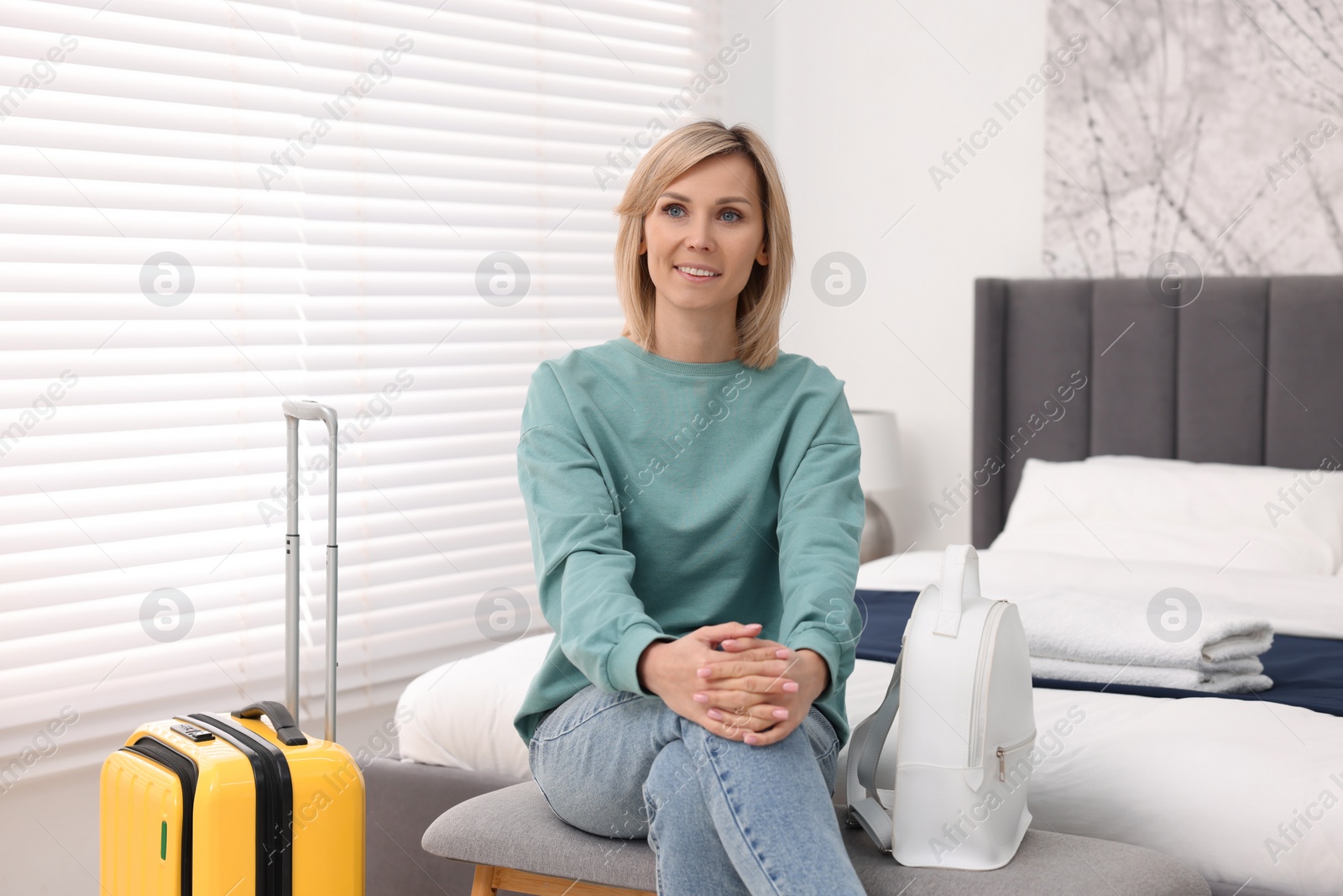 Photo of Smiling guest with backpack and suitcase in stylish hotel room