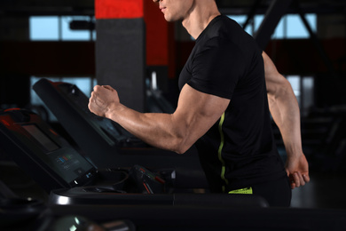 Man working out on treadmill in modern gym, closeup