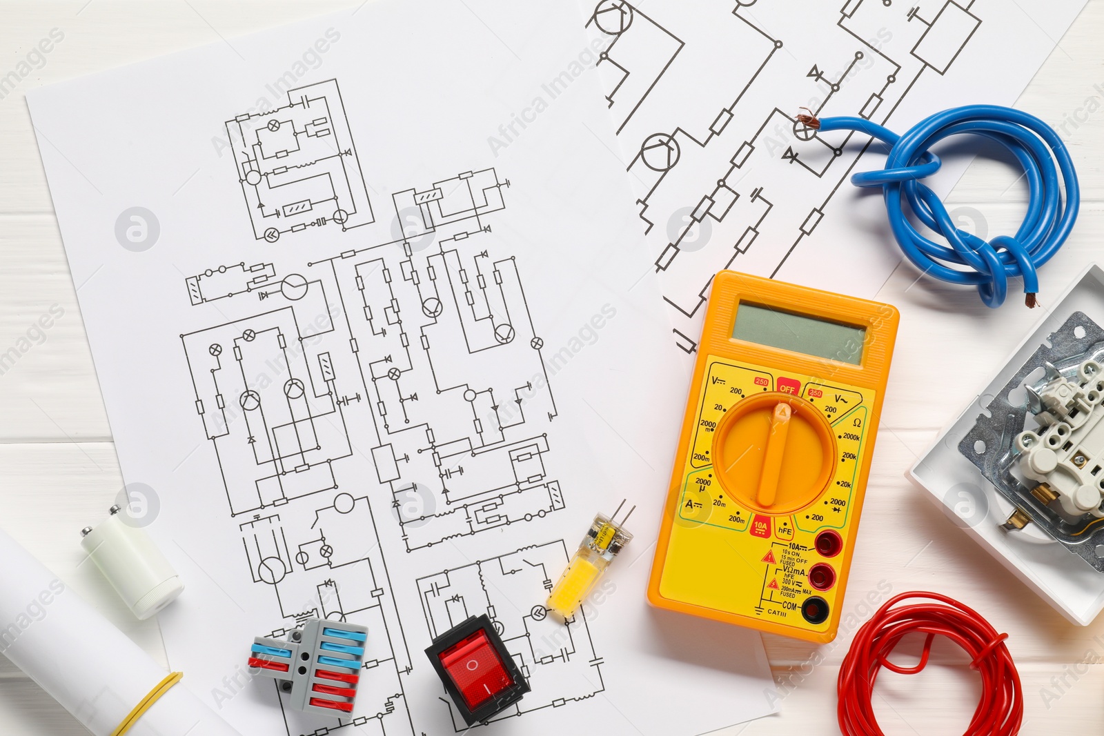 Photo of Flat lay composition with wiring diagrams and digital multimeter on white wooden table