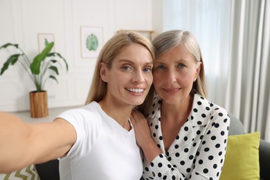 Photo of Happy daughter taking selfie with her mature mother at home