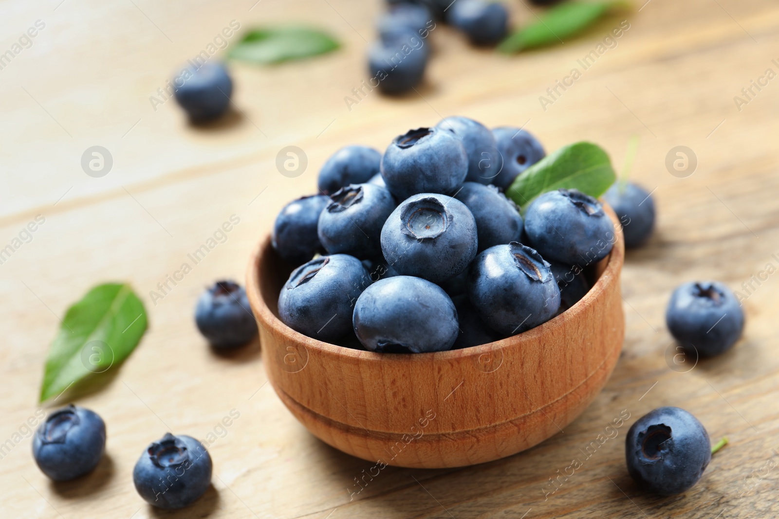 Photo of Bowl of tasty fresh blueberries on wooden table, closeup