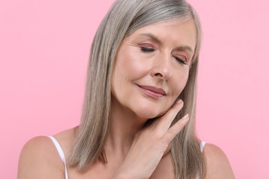 Portrait of beautiful senior woman on pink background