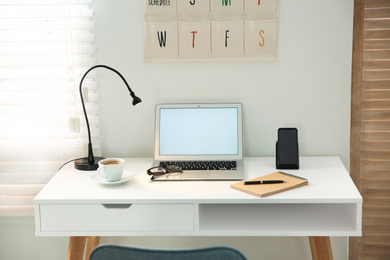 Photo of Stylish workplace with laptop, mobile phone and wireless charger