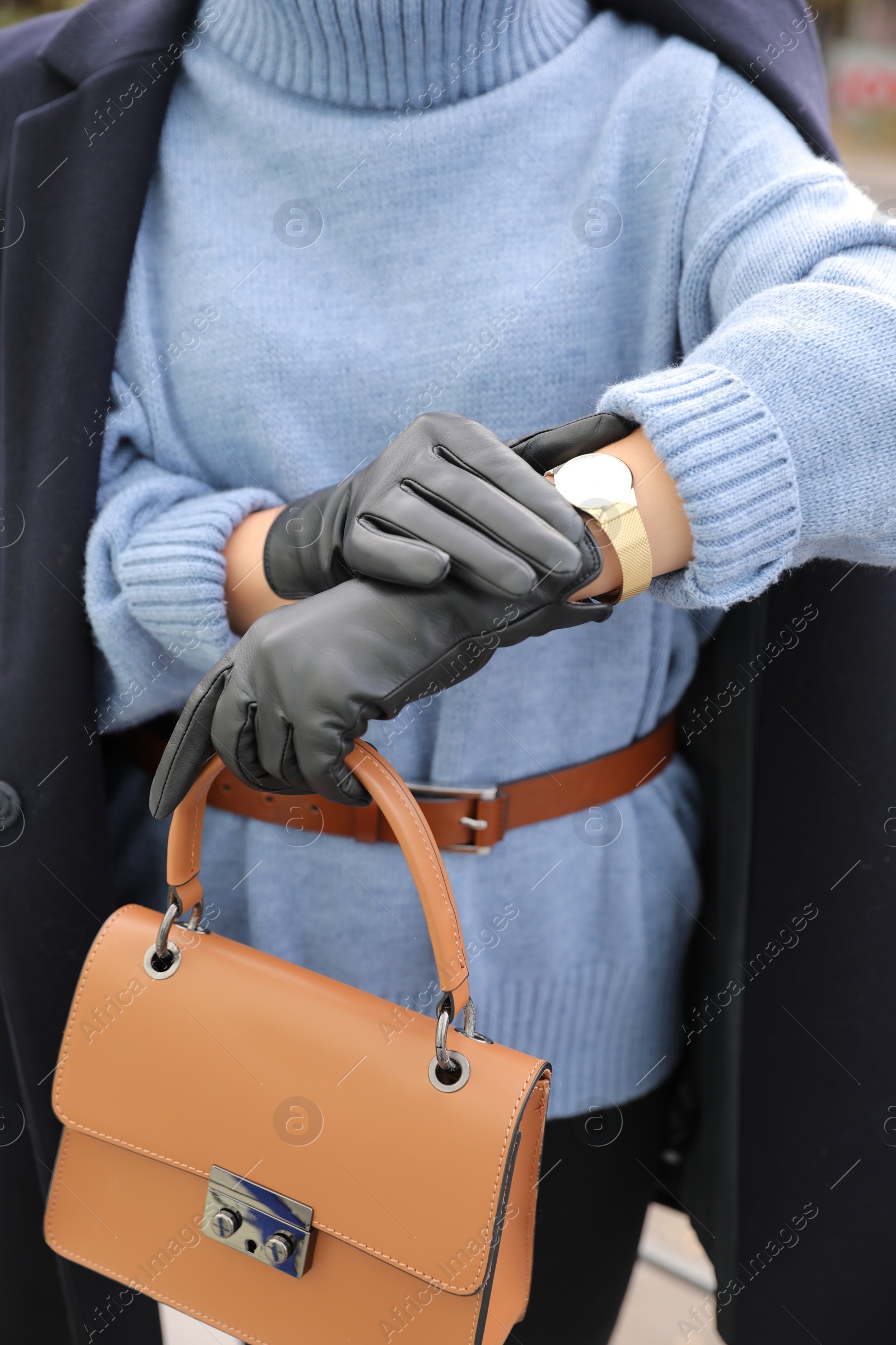 Photo of Young woman with stylish black leather gloves and bag outdoors, closeup