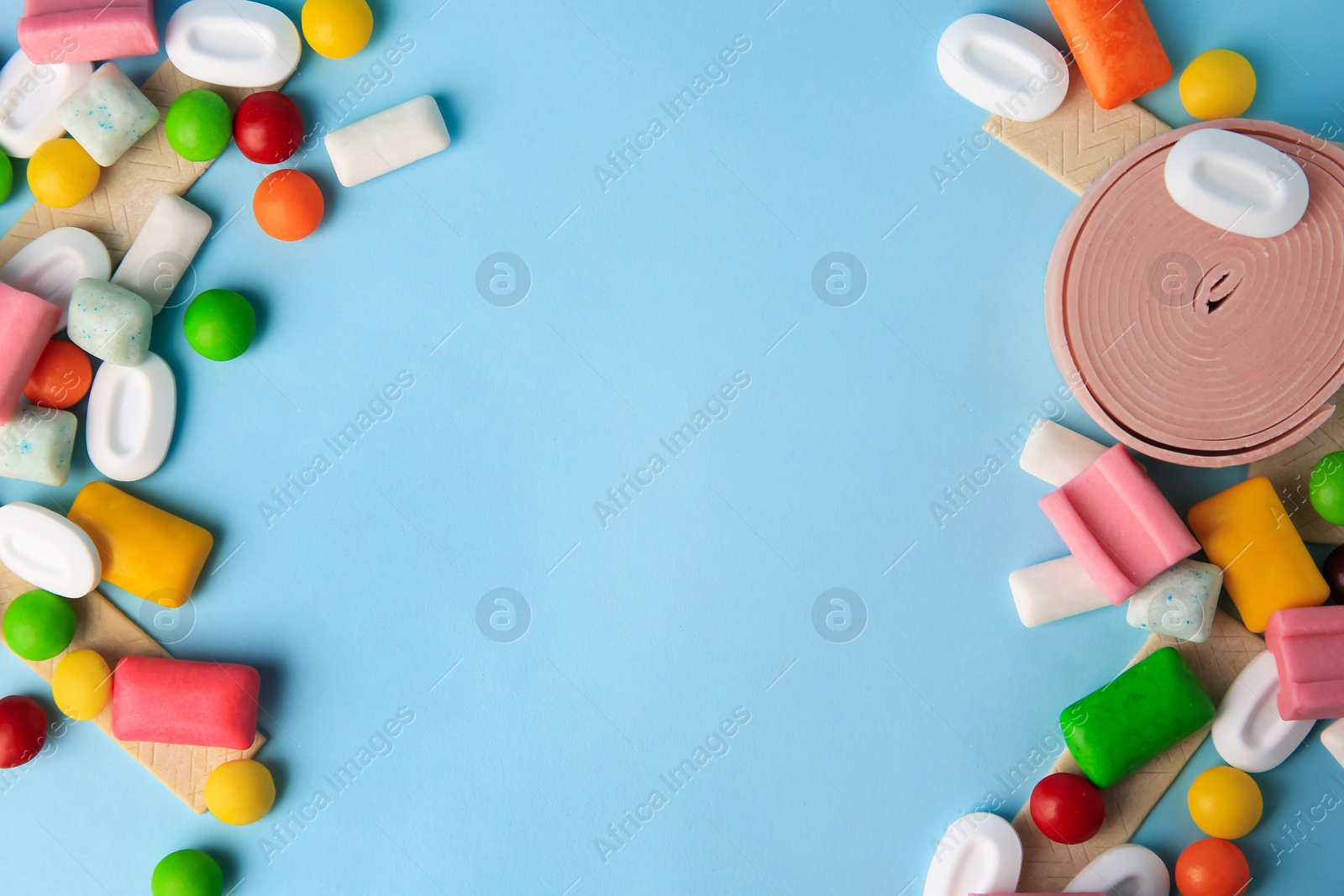 Photo of Many different chewing gums on light blue background, flat lay. Space for text