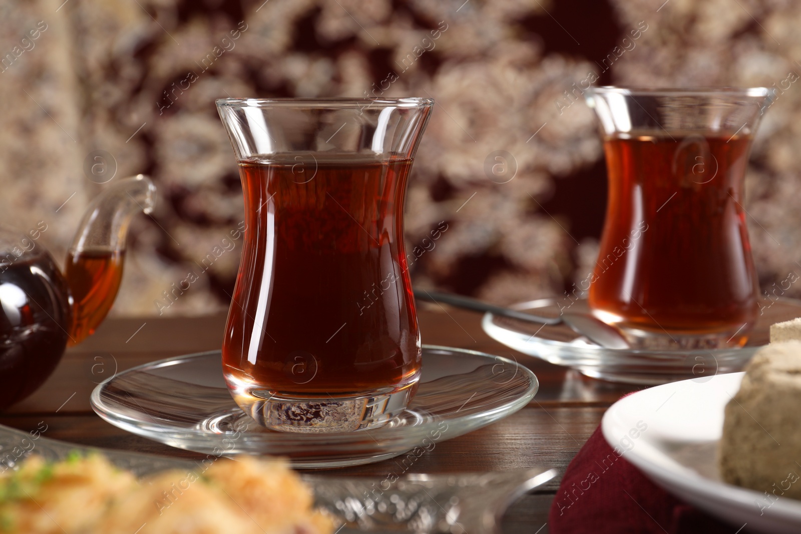 Photo of Traditional Turkish tea in glasses on wooden table, closeup