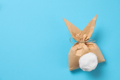 Photo of Creative Easter bunny gift bag on color background, top view with space for text