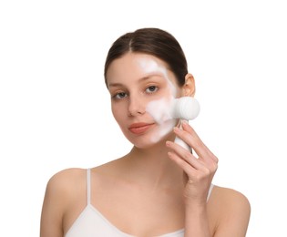 Young woman washing face with brush and cleansing foam on white background