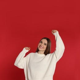 Photo of Beautiful young woman in white sweater on red background. Winter season